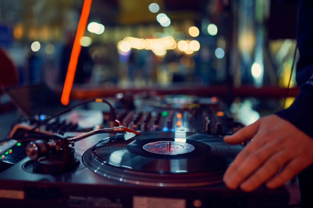 turntable, hand of dj on the vinyl record at night club. blured background